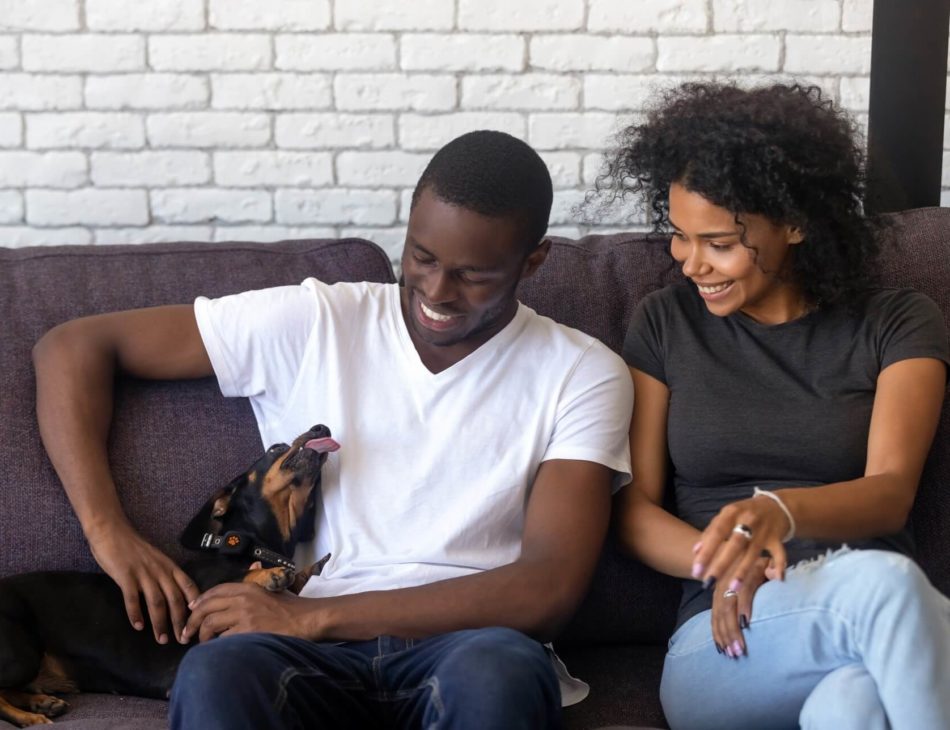 Man and woman sat on sofa with a dog